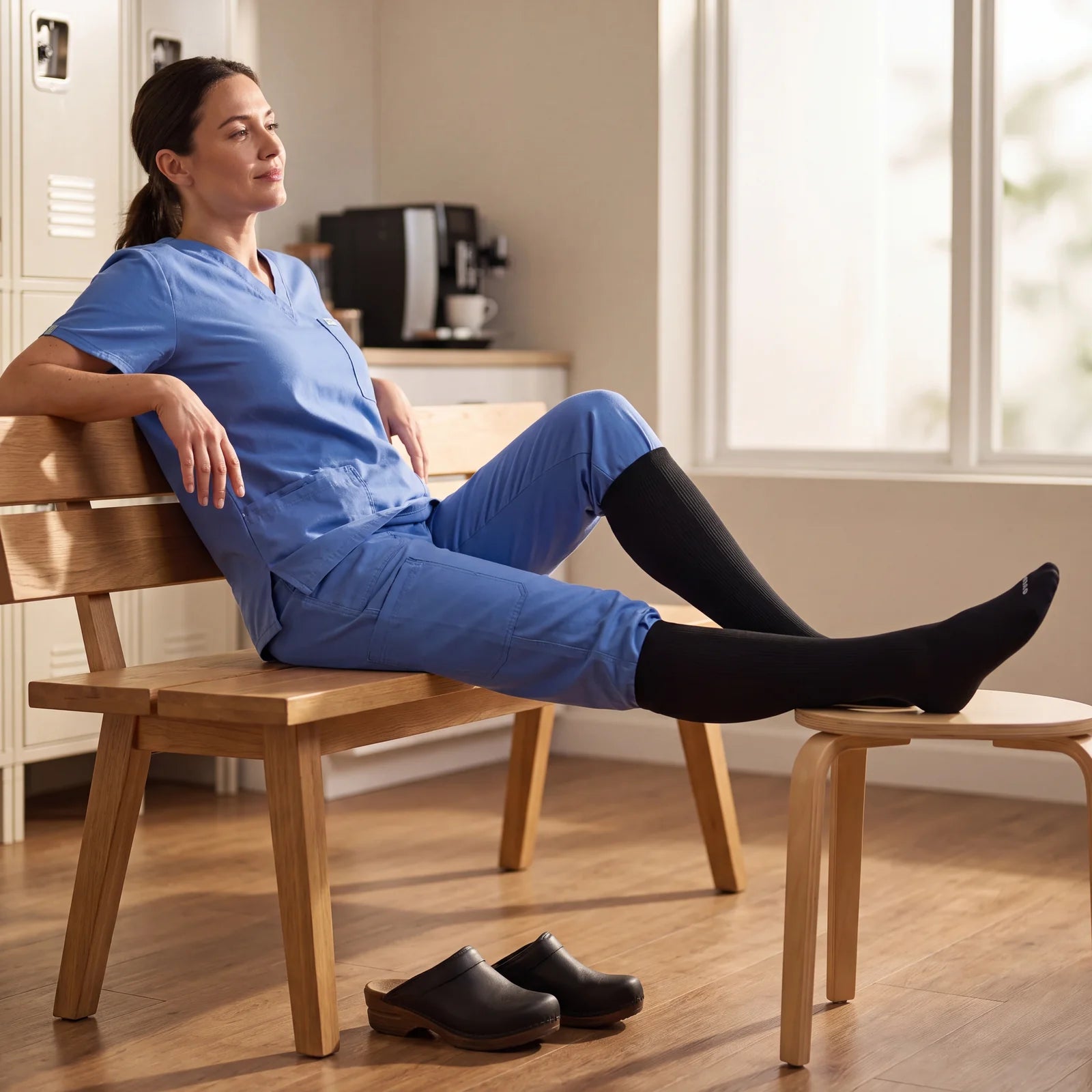 Nurse resting with legs up after a shift, wearing black OVENA compression socks